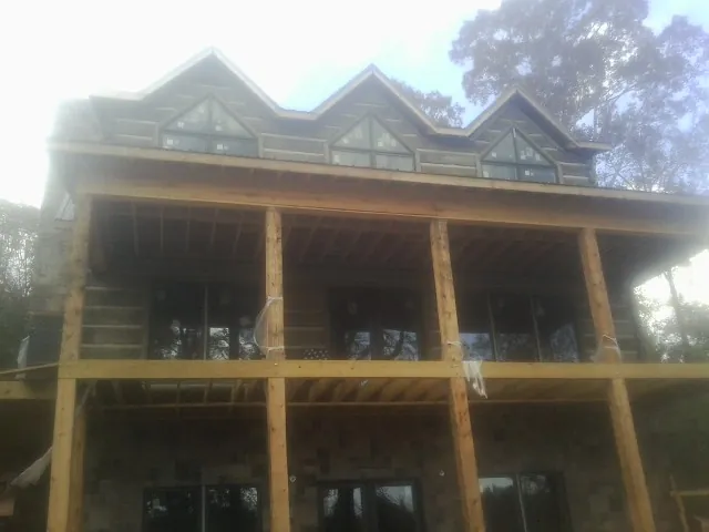 Dormers and porch framing on a large log home under construction — Roof Coating work by our crew in Cherryville