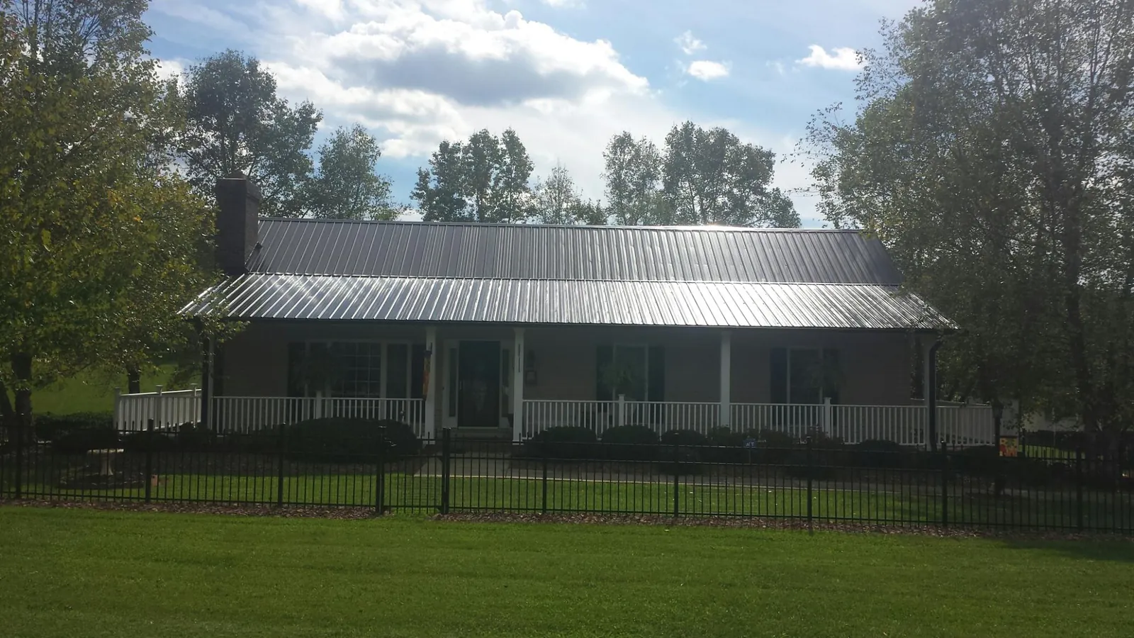 Gray metal roof on a brick ranch with a full width front porch — Gutter Guard Installation work by our crew in Cherryville