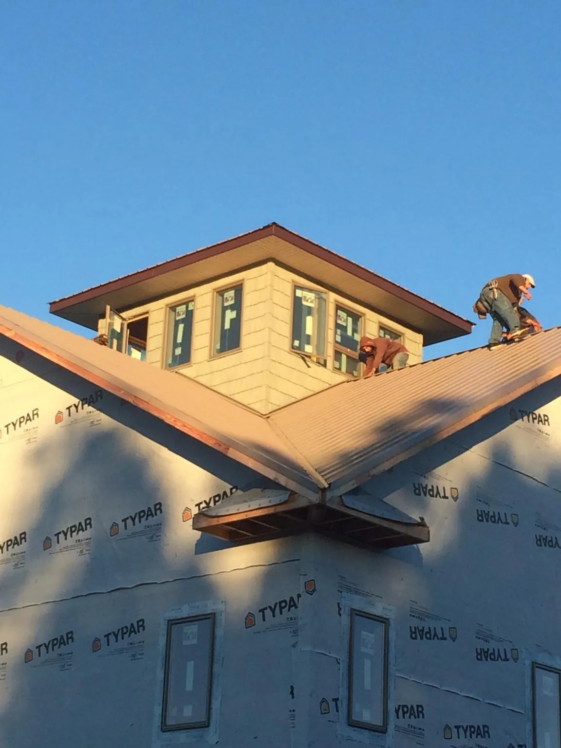 Roofers working around a rooftop cupola on a new metal roof at sunset — Roof Waterproofing in Cherryville by Roofing Brothers